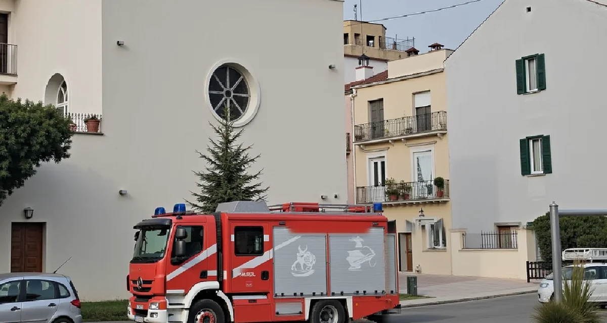 Autopompa dei vigili del fuoco parcheggiata davanti a una chiesa e a palazzine in una piazza italiana